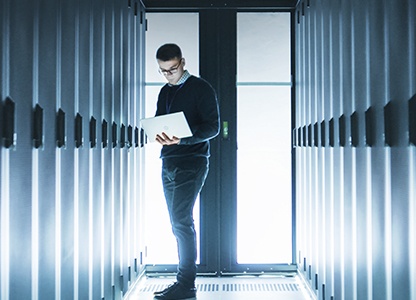 A man standing near the server rack with a laptop